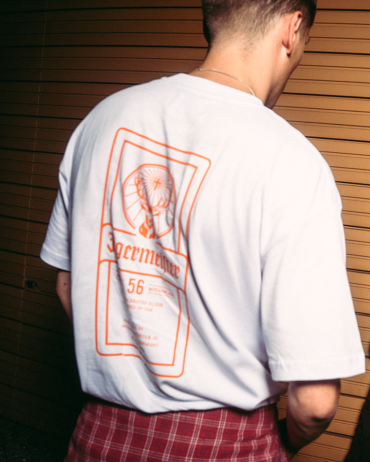 Vista posteriore di una T-shirt bianca Jägermeister con una grande stampa grafica ispirata all’etichetta Jägermeister.