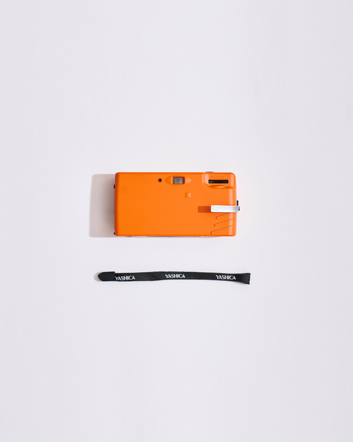 Fotocamera arancione con tracolla su sfondo bianco
