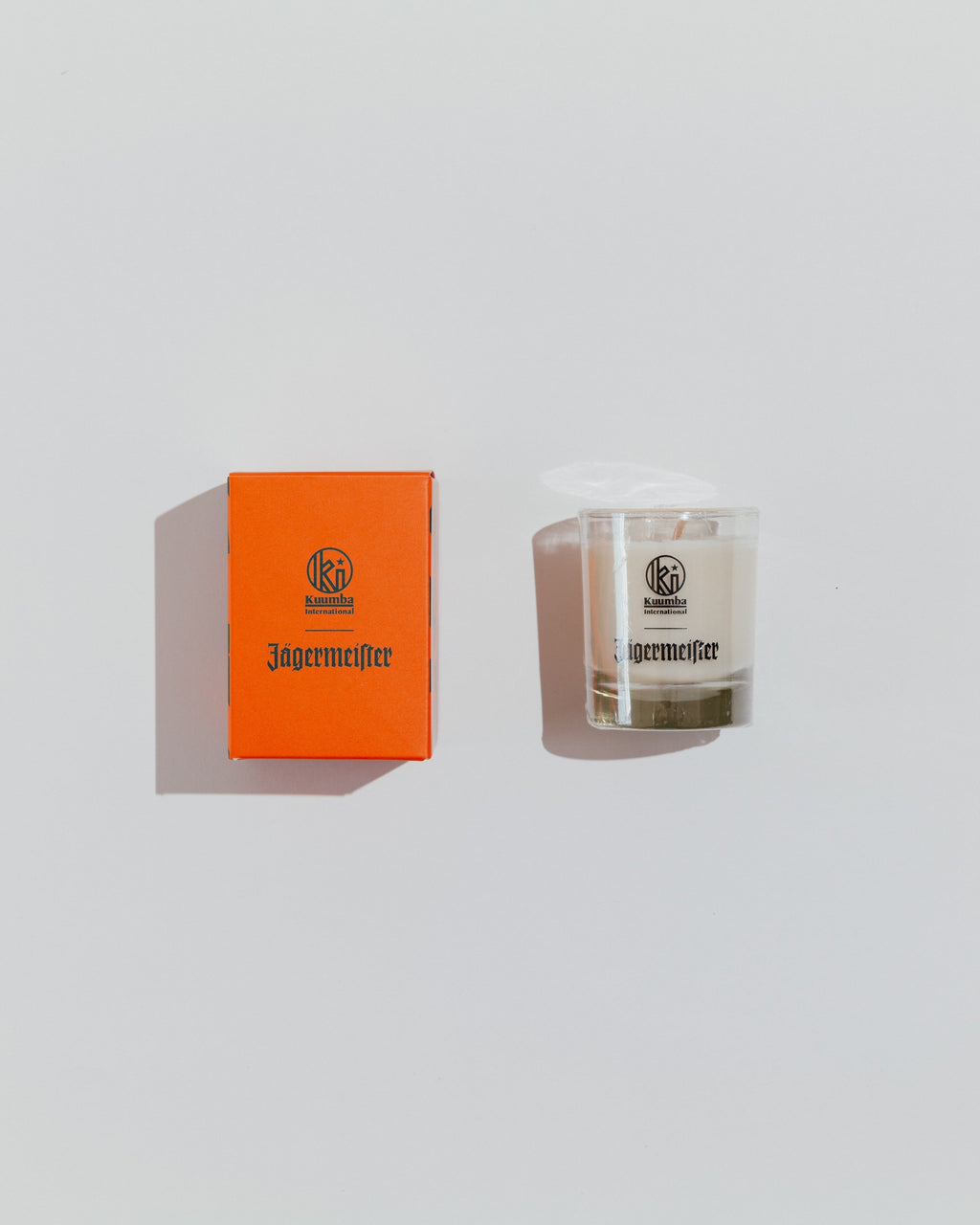 Candela Jägermeister e scatola arancione su uno sfondo grigio chiaro