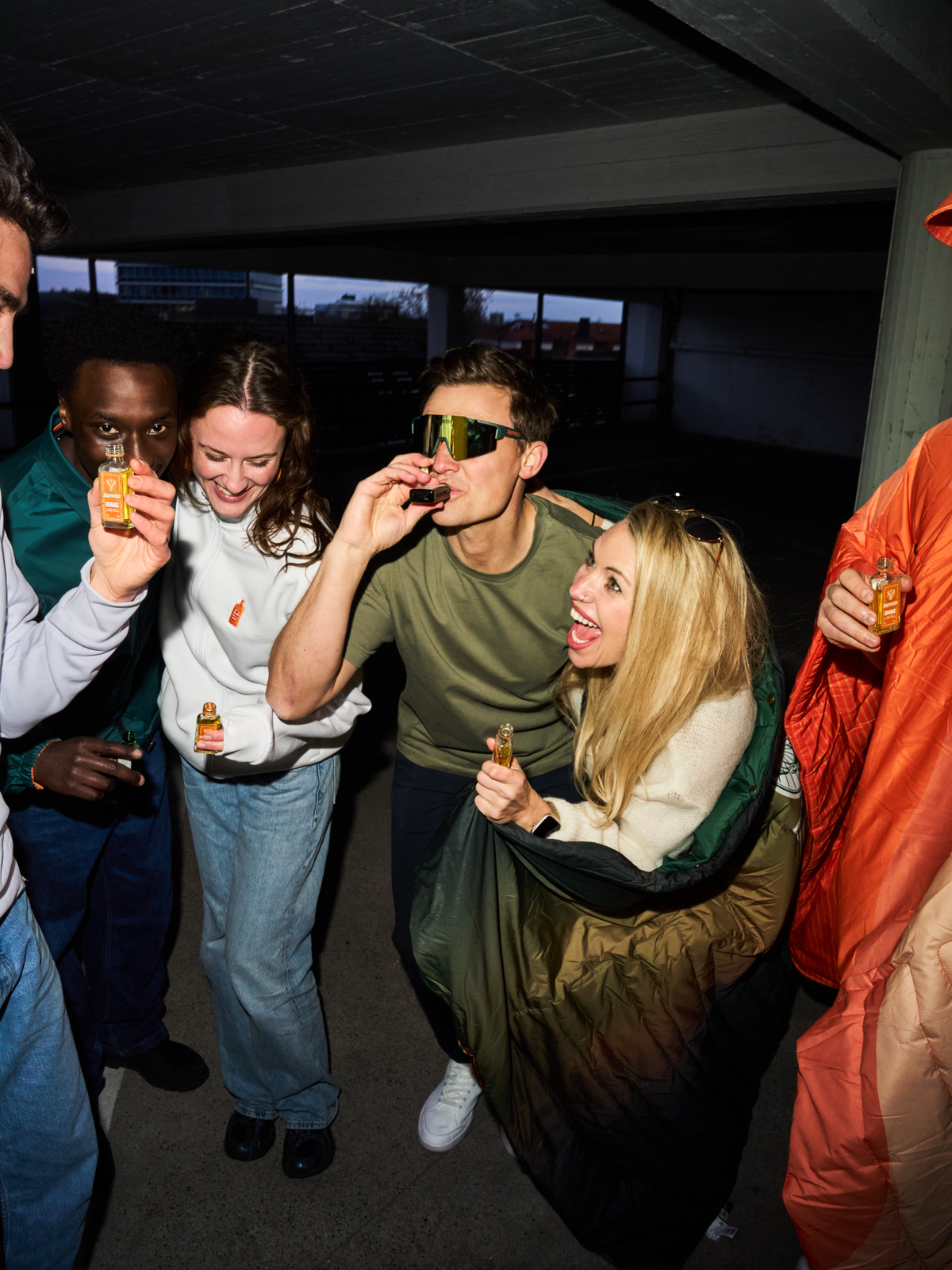 Gruppo di persone che beve shot Jägermeister a un incontro sociale, con una persona che indossa gli occhiali Jägermeister Fast Glasses con lenti a specchio e un design aerodinamico.