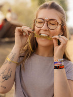 Donna con collana Jägermeister con catena dorata e bracciali in un contesto da festival.