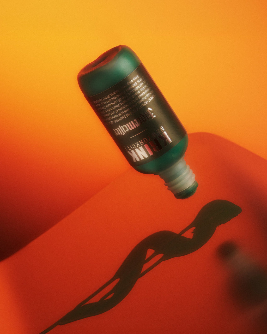 Pennarello verde Krink con branding Jägermeister su sfondo sfumato rosso e arancione