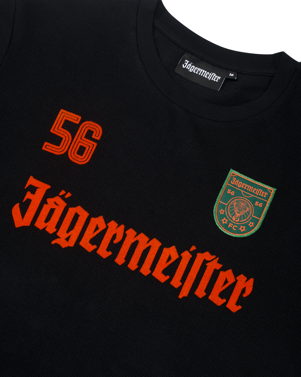 Maglia nera a maniche lunghe Jägermeister con branding e logo arancioni.