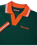 Abito polo verde con colletto e rifiniture arancioni con branding Jägermeister.