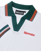 Dettaglio ravvicinato di abito polo bianco con colletto verde e accenti arancioni, con branding Jägermeister.