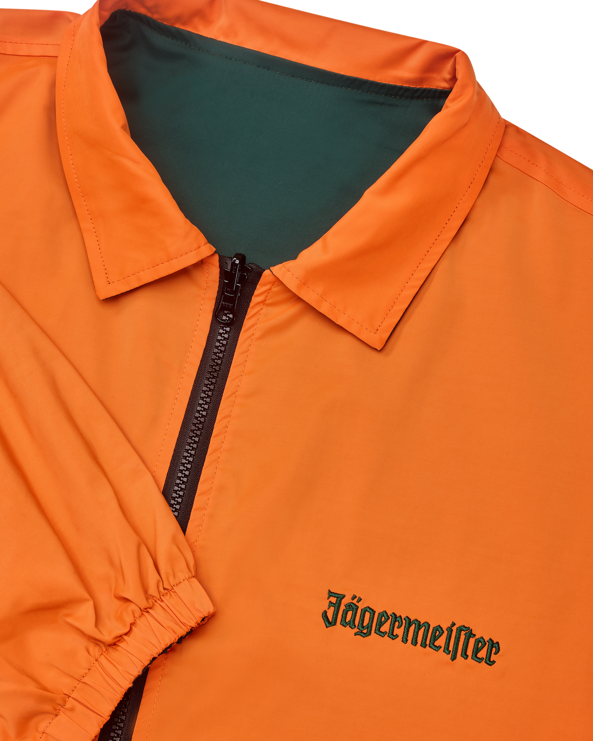 Primo piano della giacca reversibile Jägermeister con cerniera, con il lato arancione visibile