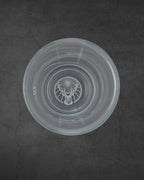 Bicchiere shot Jägermeister bianco visto dall’alto con logo del cervo sul fondo
