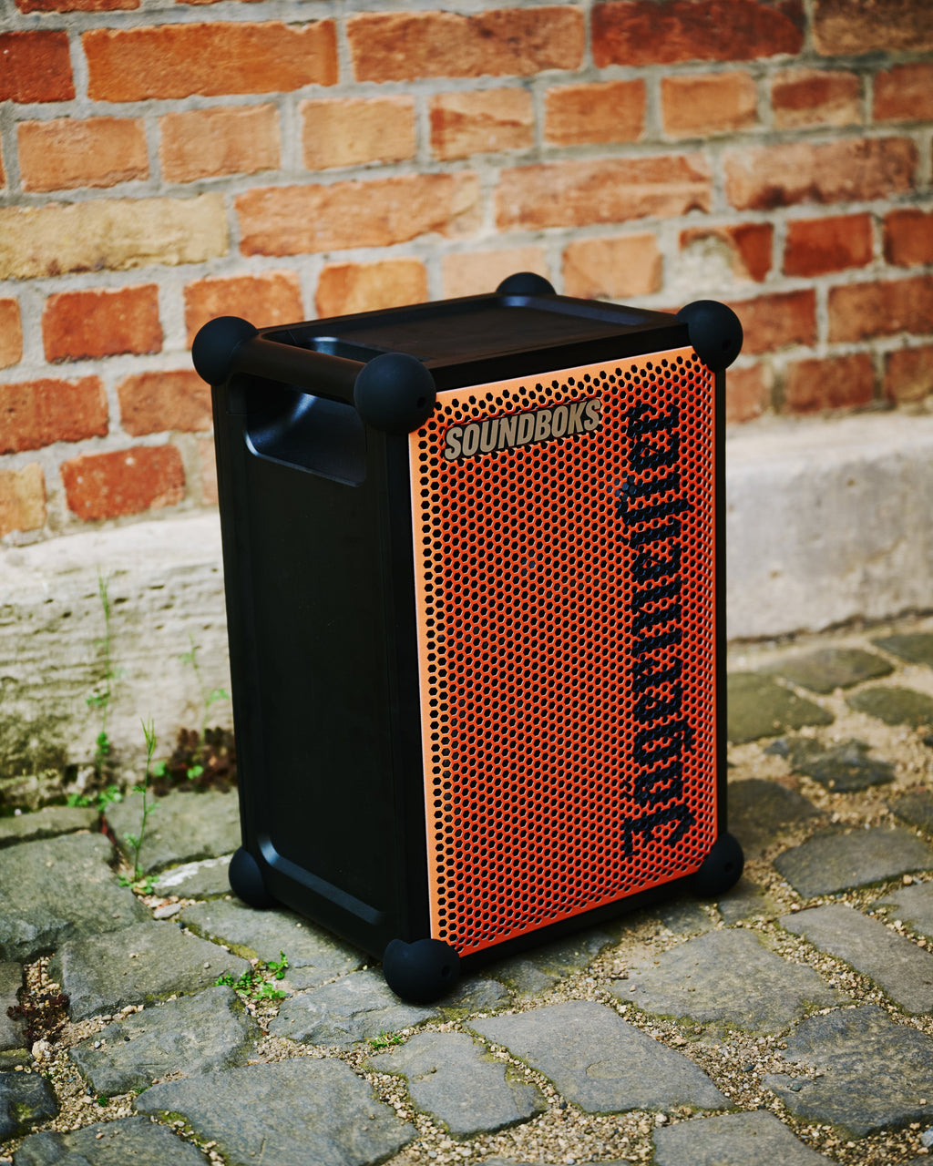 Speaker portatile Soundboks arancione e nero con branding 'Jägermeister' contro una parete di mattoni