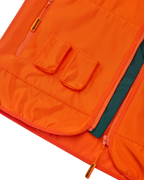 Primo piano di un gilet arancione Jägermeister con due tasche frontali per i Jägermeister Minis.