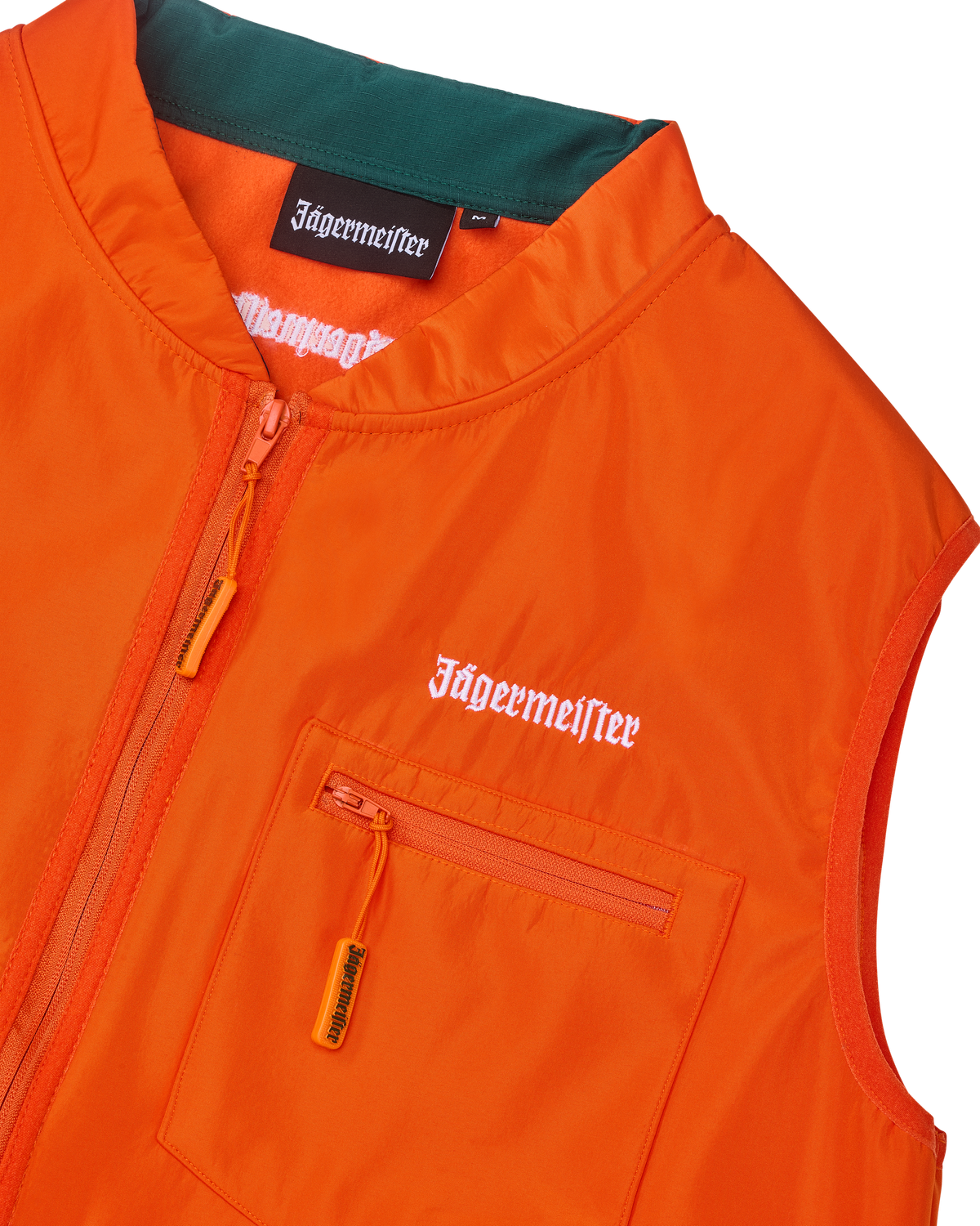 Primo piano di un gilet arancione con branding Jägermeister bianco.