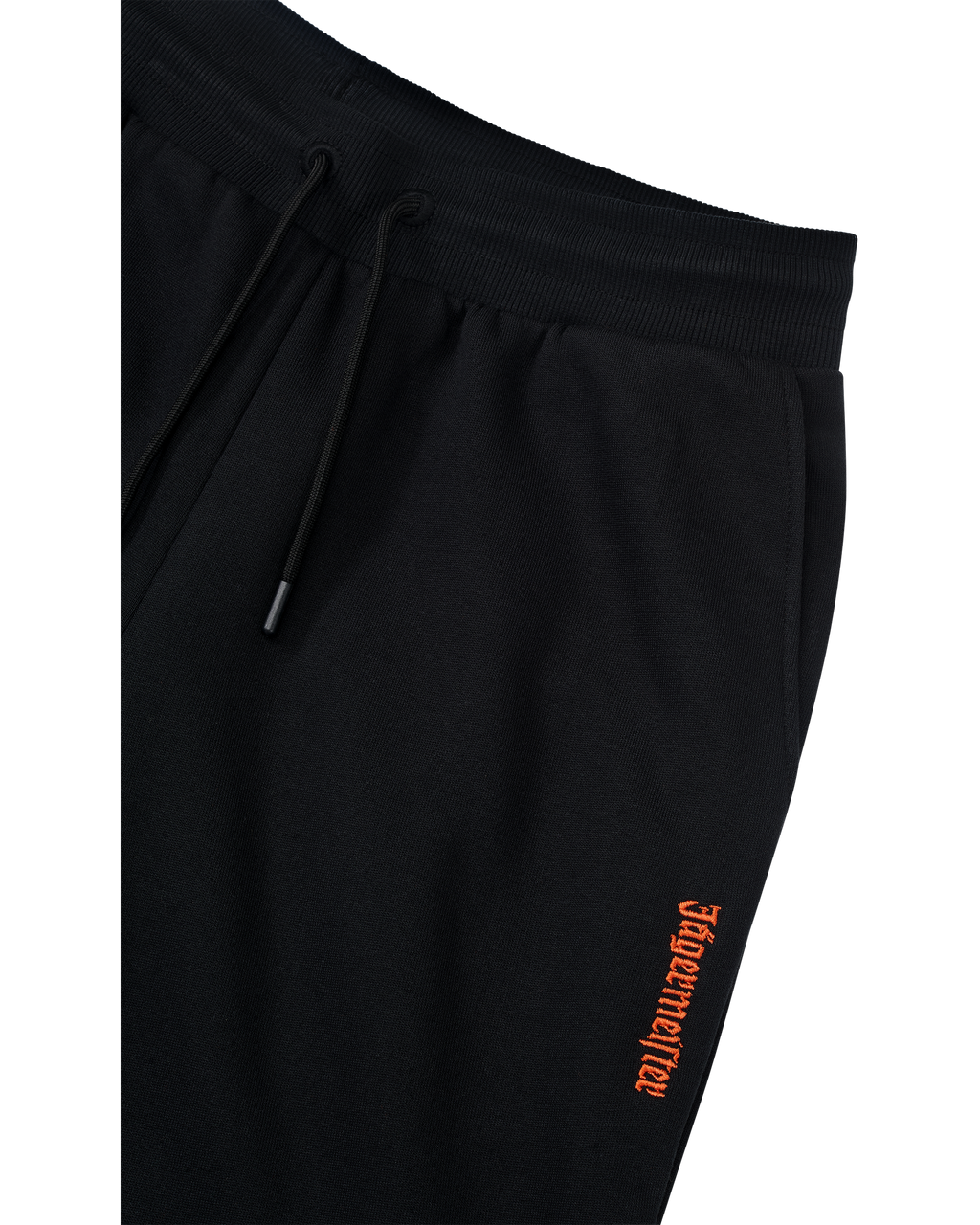 Pantaloni della tuta neri con logo Jägermeister arancione sul lato.