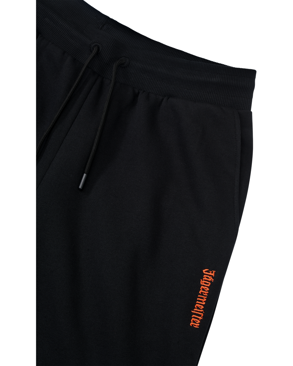 Pantaloni della tuta neri con logo Jägermeister arancione sul lato.